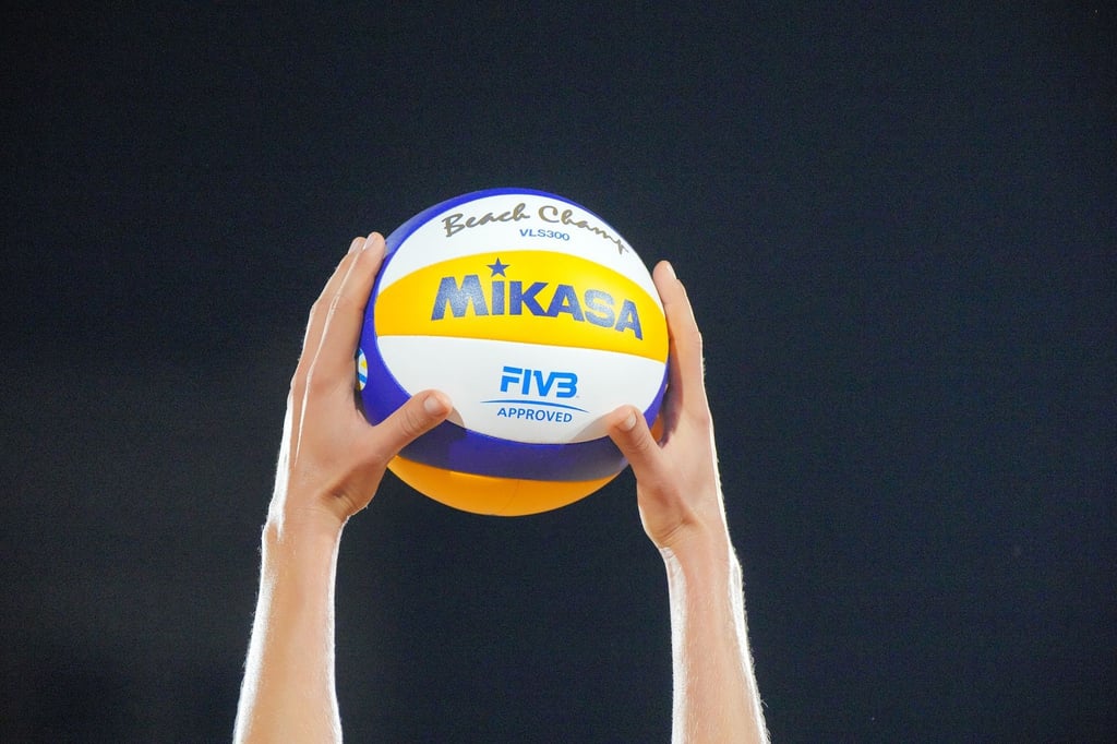Eine Spielerin hält einen Volleyball mit beiden Händen vor der Aufgabe nach oben.