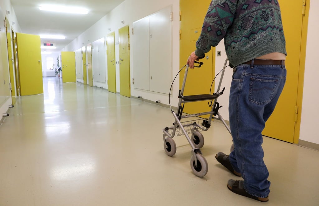 Ein Häftling im Rentenalter geht mit einem Rollator über den Flur im Seniorentrakt der JVA Waldheim.