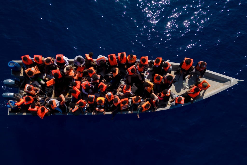 Menschen sitzen in einem Holzboot im Mittelmeer. Symbolbild