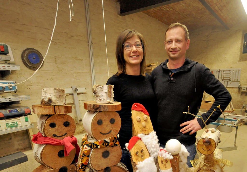 Katharina und Tobias Fehse stehen vor ihren - fertig montierten - Holzbausatz-Kreationen aus den zurückliegenden Jahren: Von Schnee- sowie Weihnachtsmännern über Elche bis hin zu Nagelbildern reicht die Bandbreite.