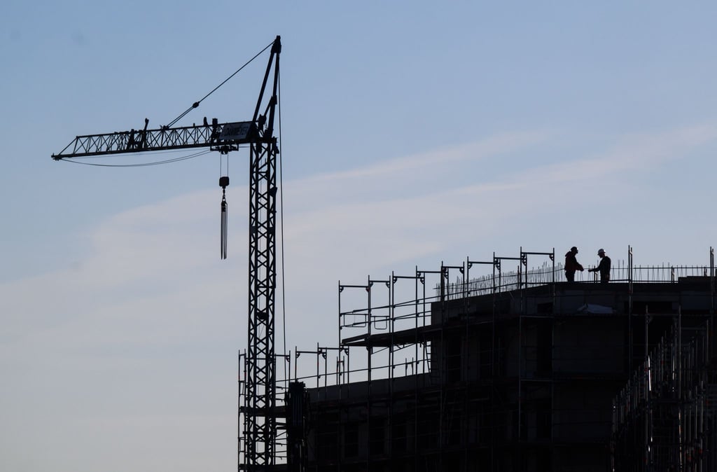 Bauarbeiter stehen auf der Baustelle eines Mehrfamilienhauses.