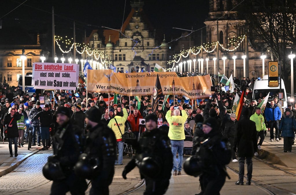 Teilnehmer einer Demonstration der rechtsextremistischen Bewegung Pegida laufen über die Augustusbrücke.
