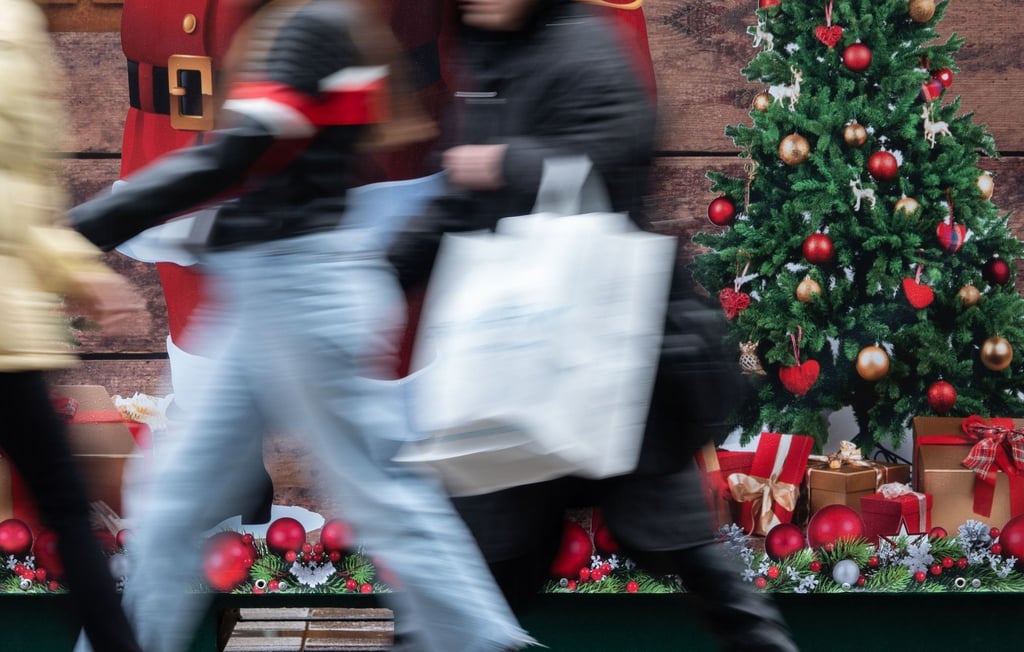 Passanten gehen an einem weihnachtlich geschmückten Verkaufsstand vorbei.
