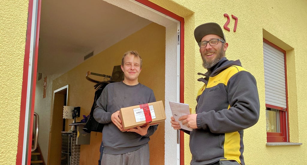 Sven Mens bekommt von Stefan Kleinert ein Paket nach Hause geliefert.