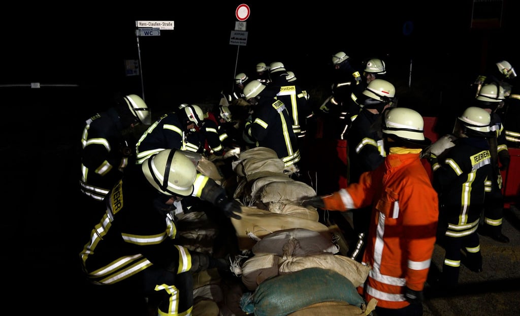Einsatzkräfte der Feuerwehr sichern eine Deichschart mit Sandsäcken.