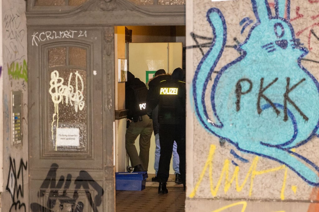 Polizeibeamte gehen während der Durchsuchungsaktion über einen Flur in einem Berliner Mietshaus.
