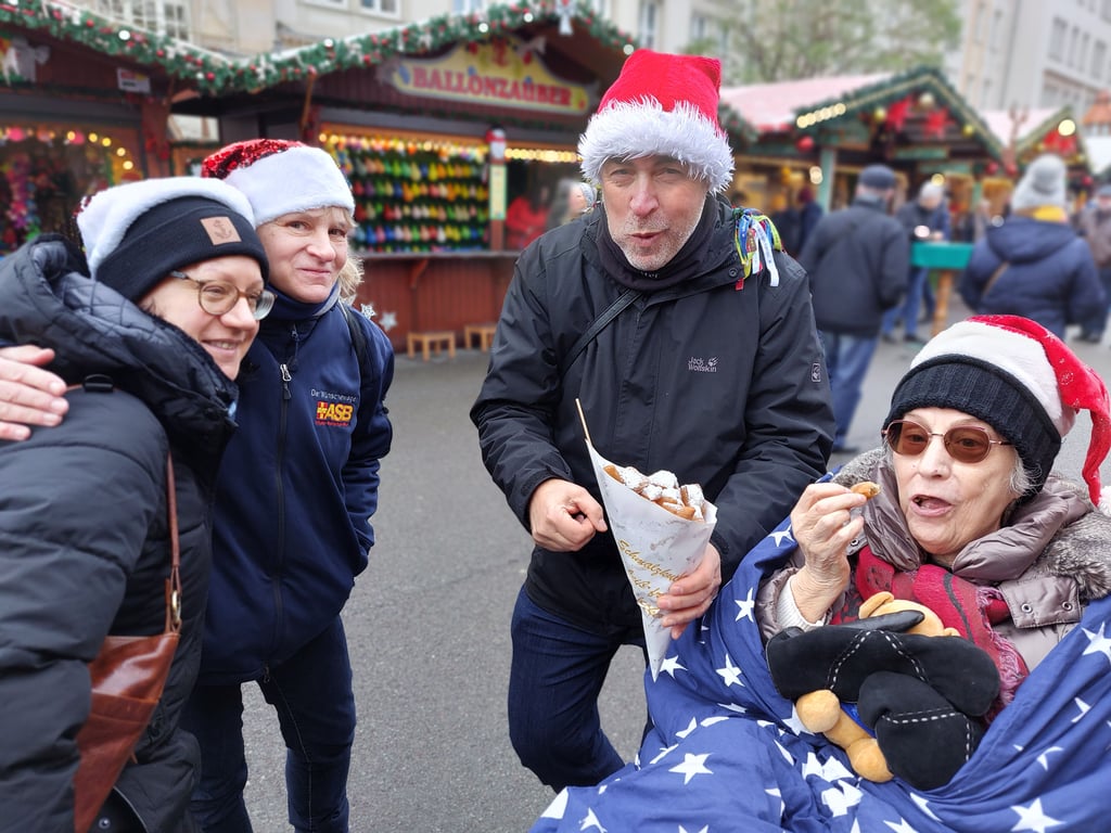Mit dem Wünschewagen noch einmal auf den Weihnachtsmarkt: Sybille Leitel (r.) mit Tochter Anke Kählert (l.) sowie den ASB-Wunscherfüllernfüllern Simone und Holger Frank auf dem Magdeburger Weihnachtsmarkt.