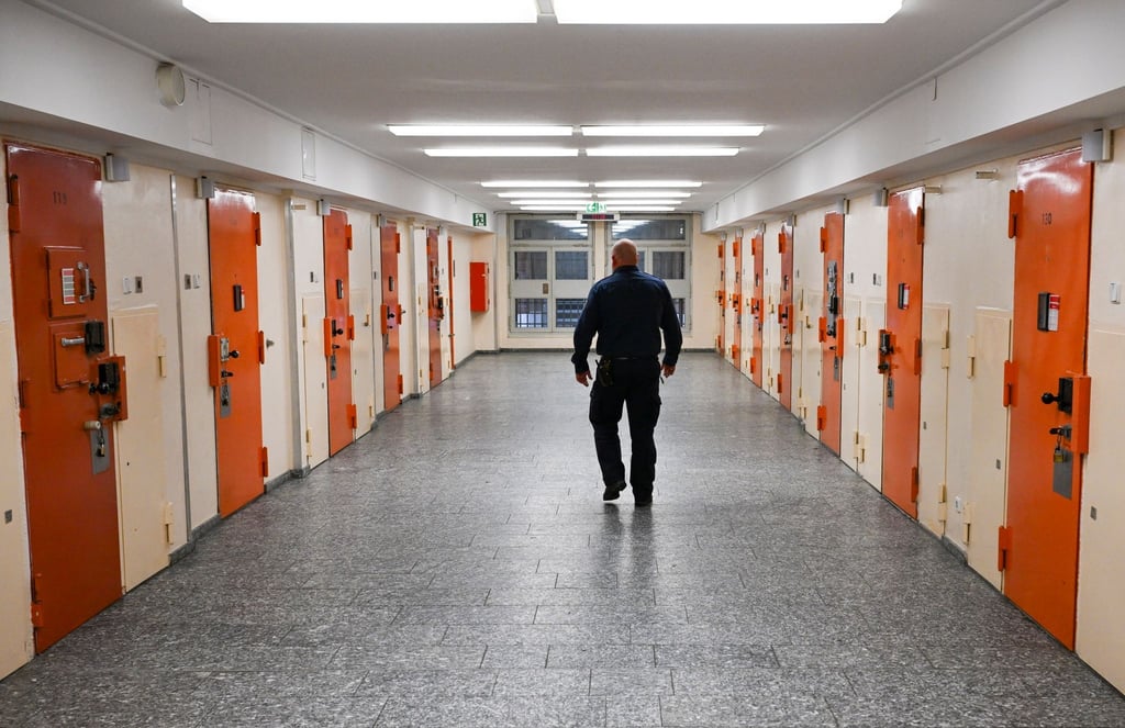 Ein Vollzugsbeamter geht in der Justizvollzugsanstalt Moabit an Zellentüren vorbei.