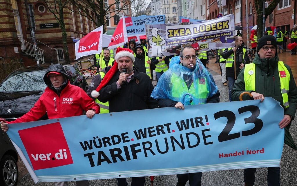 Teilnehmerinnen und Teilnehmer eines Warnstreiks ziehen mit Fahnen der Gewerkschaft Verdi durch die Stadt.