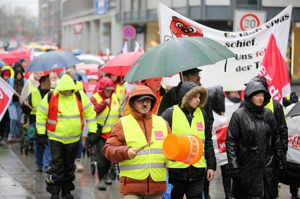 Teilnehmer einer Verdi-Kundgebung gehen mit Plakaten durch die Innenstadt.
