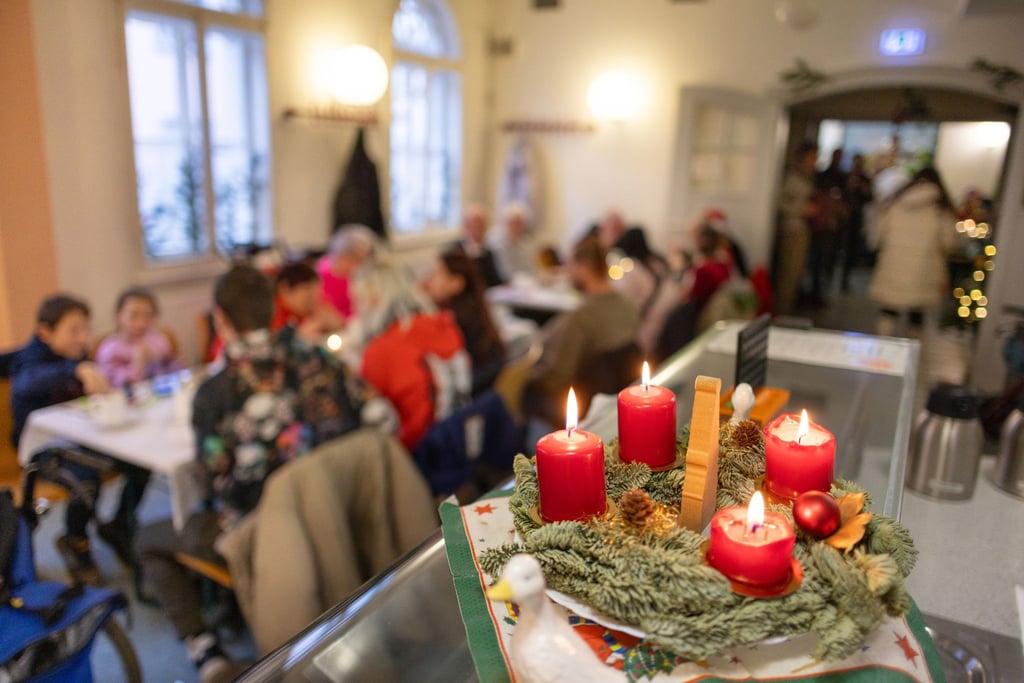Vier Kerzen brennen an einem Adventskranz bei der Weihnachtsfeier in der Suppenküche der Caritas.