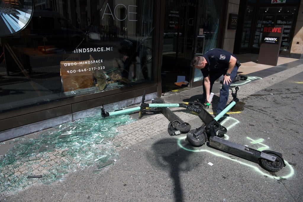 Ein Polizist markiert nach einem Verkehrsunfall E-Scooter.