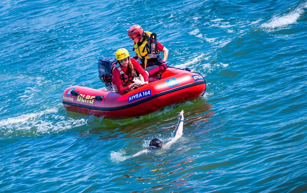 Zwei DLRG-Rettungsschwimmerinnen ziehen bei einer Rettungsübung eine Frau aus dem Wasser der Ostsee.