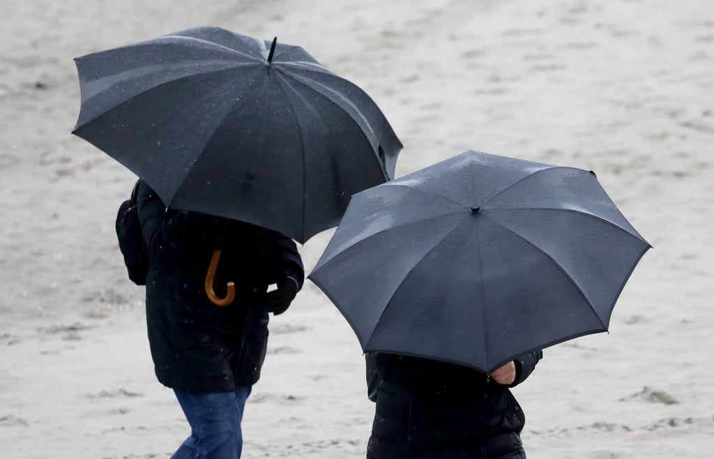Spaziergänger gehen bei Wind und Regen spazieren.