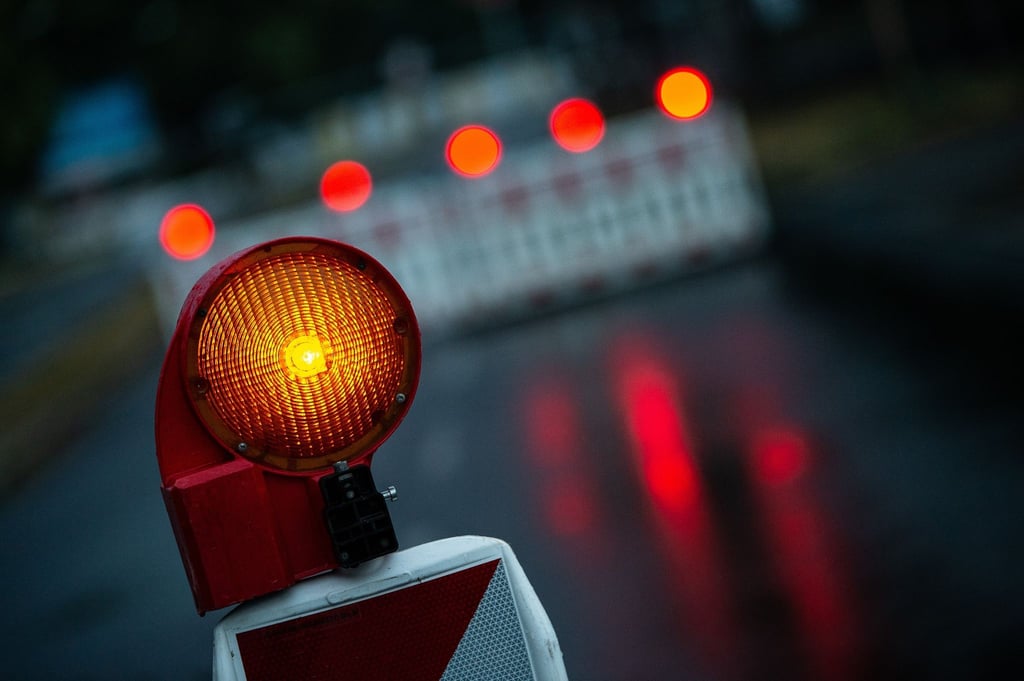 Eine Warnleuchte steht an einem abgesperrten Bereich auf einer Straße.