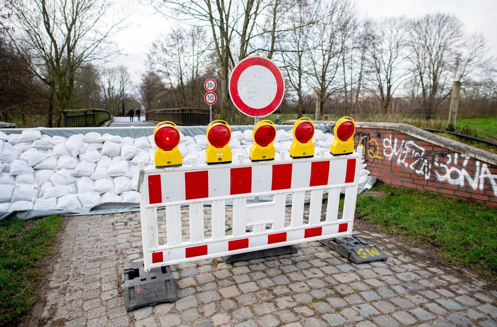 Zahlreiche Sandsäcke liegen vor einer gesperrten Deichschart.
