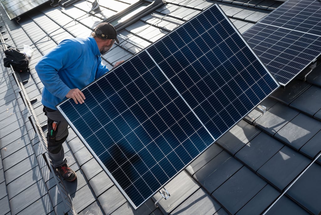 Mitarbeiter einer Solarfirma montieren Photovoltaikmodule auf dem Dach eines Wohnhauses.