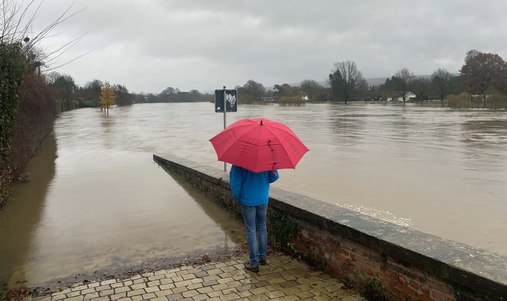 Ein Mann blickt auf einen weit über die Ufer getretenen Fluss. In Mitteldeutschland werden weitere Regenfälle erwartet.