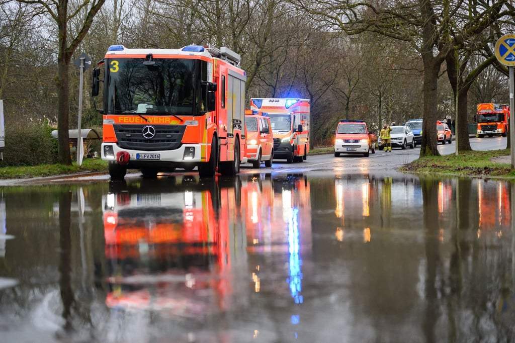 Einsatzkräfte der Feuerwehr Hannover stehen bei einem Einsatz auf einer überfluteten Straße.