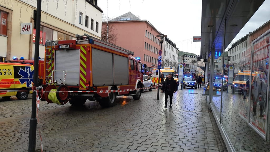 Einsatzkräfte von Feuerwehr und Rettungsdienst stehen am Freitag in der Innenstadt am Einsatzort.