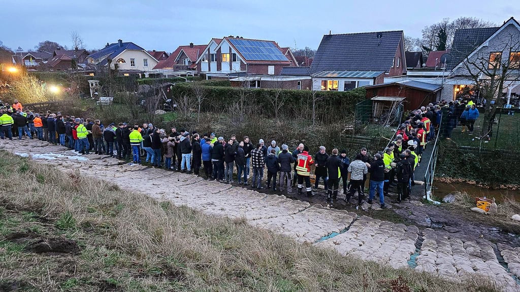 Einsatzkräfte und Einwohner sichern gemeinsam einen durchweichten Deich in Haren.