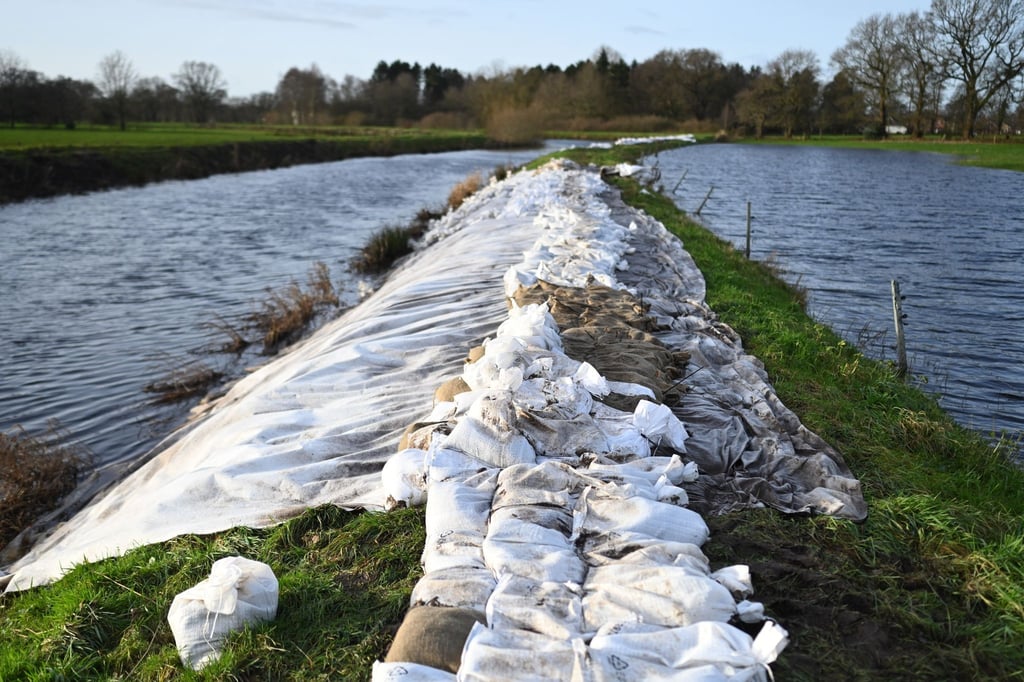 Sandsäcke liegen an einem Fluss.