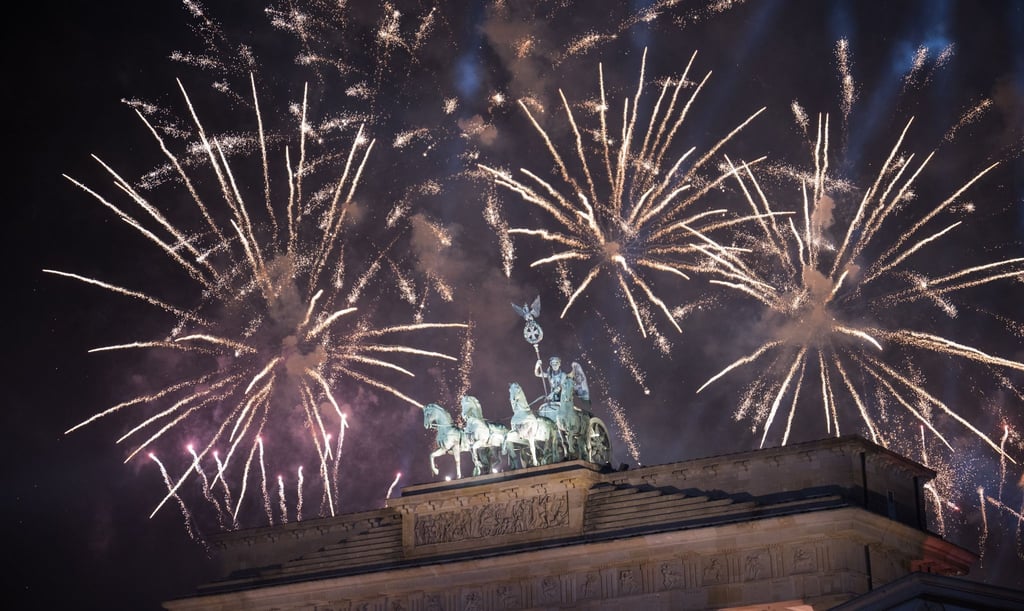 Feuerwerk zum Jahreswechsel steigt während der Feier „Silvester am Brandenburger Tor“ hinter dem Brandenburger Tor auf.