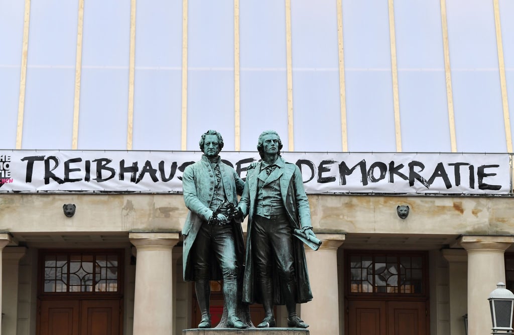 "Treibhaus der Demokratie" steht an der Fassade des Deutschen Nationaltheater hinter dem Goethe-Schiller-Denkmal.