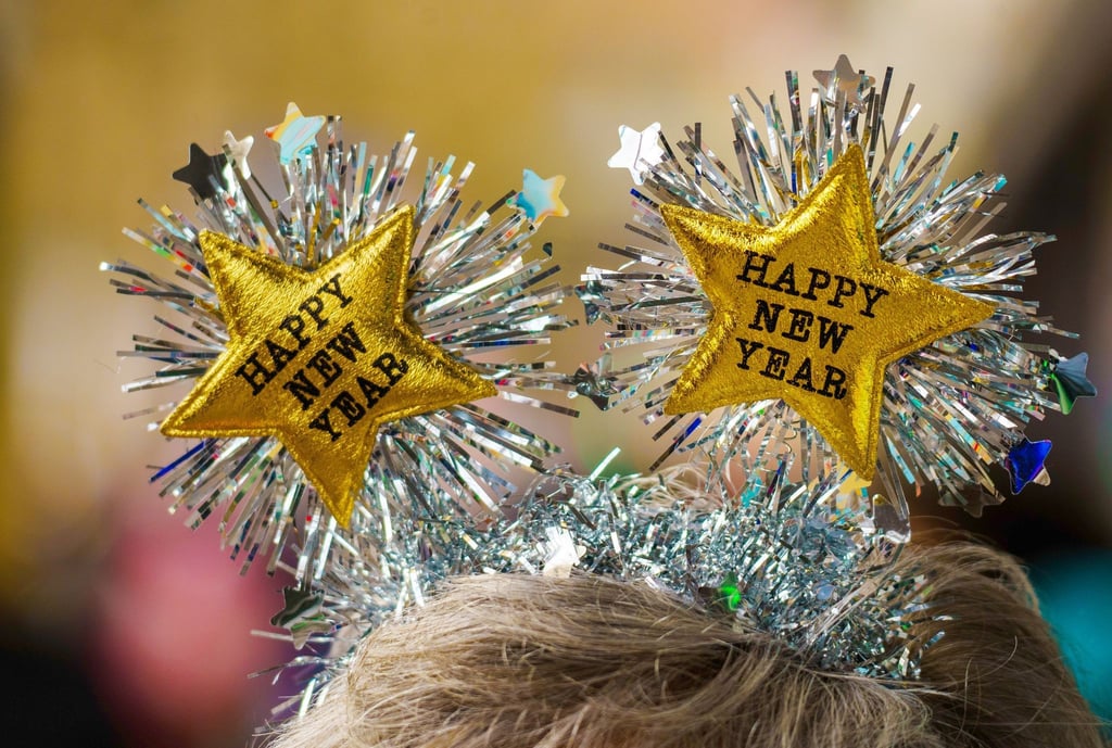 Ein Frau begrüßt das Neue Jahr mit einem passendem Kopfschmuck mit der Aufschrift "Happy New Year" (Frohes Neues Jahr) in der Mainzer Innenstadt.