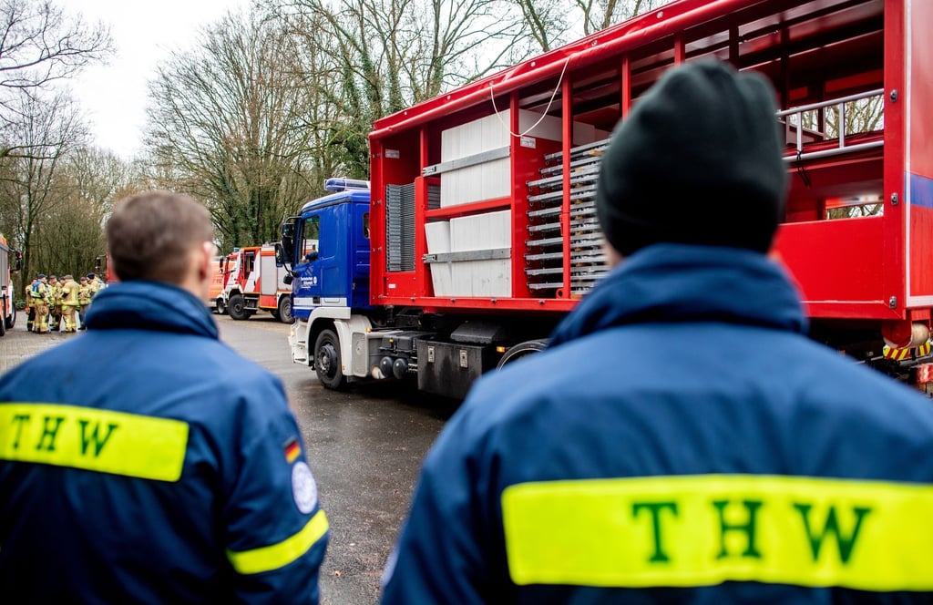 Einsatzkräfte des Technischen Hilfswerks (THW) stehen vor einem LKW.