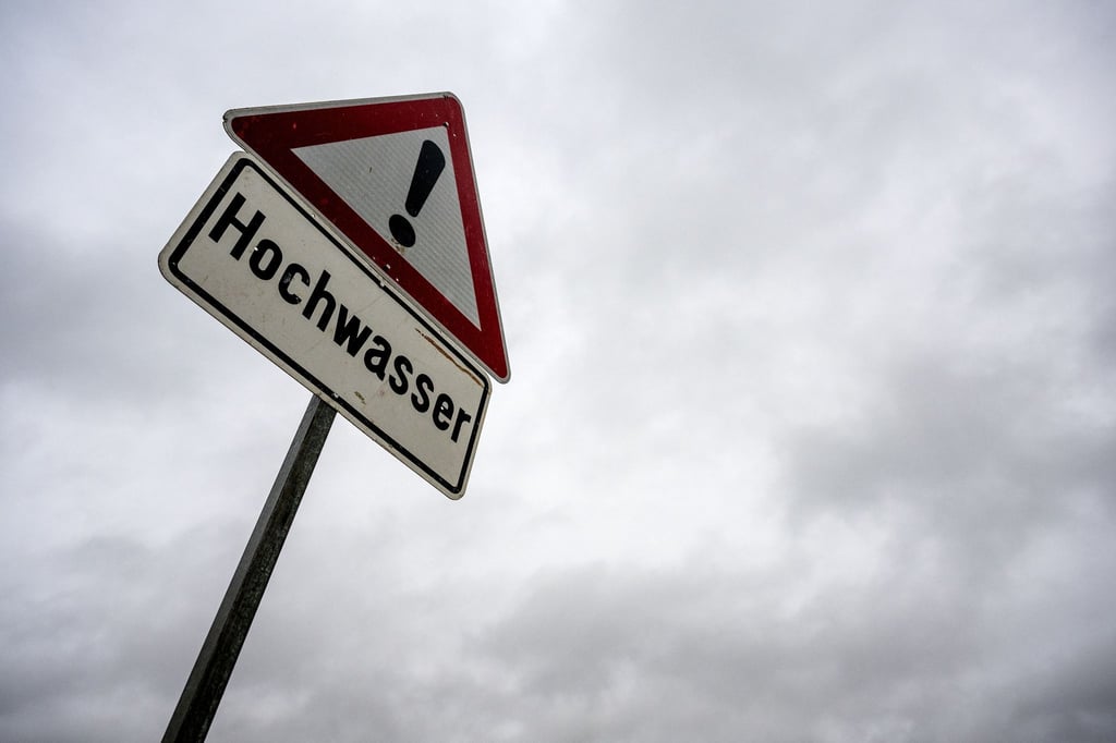 Ein Schild warnt vor Hochwasser, der Himmel über ihm verheißt weiteren Regen.