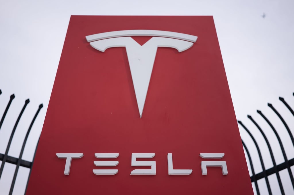 Ein Tesla-Schild vor einem Tesla-Autohaus.