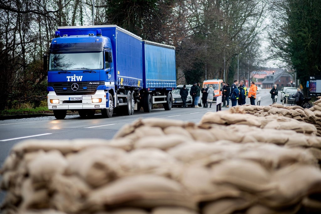 Einsatzkräfte des THW sichern ein Wohnhaus vor dem drohenden Hochwasser mit Sandsäcken.