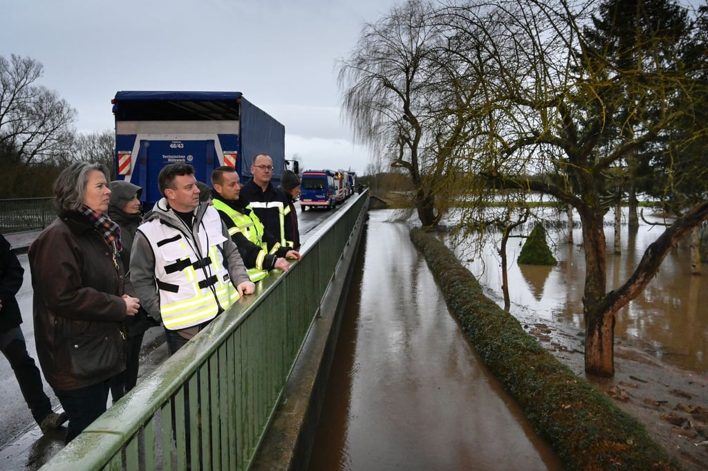 Tamara Zieschang, Innenministerin von Sachsen-Anhalt, und André Schröder (2.v.l.), Landrat Mansfeld-Südharz, stehen auf der Helme-Brücke und schauen sich die Auswirkungen der Überflutung an.