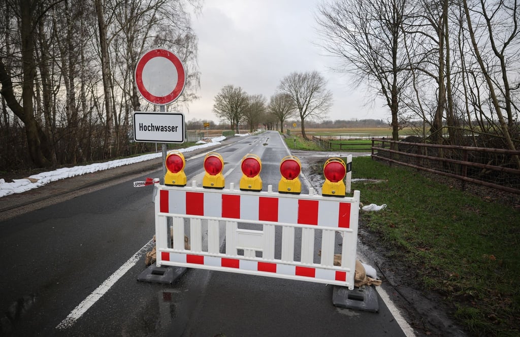 Eine Hochwasser-Absperrung steht auf einer Landstraße am Ortsausgang von Sandkrug bei Oldenburg.