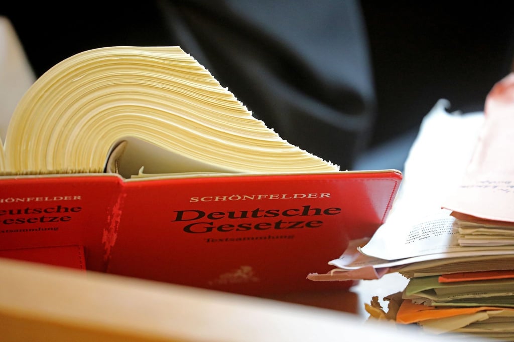 Ein Referendar sitzt im Landgericht vor einem Textband „Deutsche Gesetze“.
