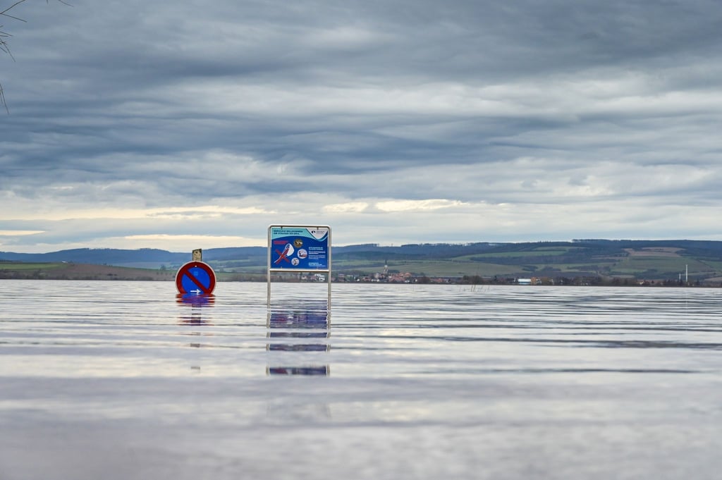 Schilder stehen im Hochwasser auf dem Campingplatz an der Talsperre Kelbra.