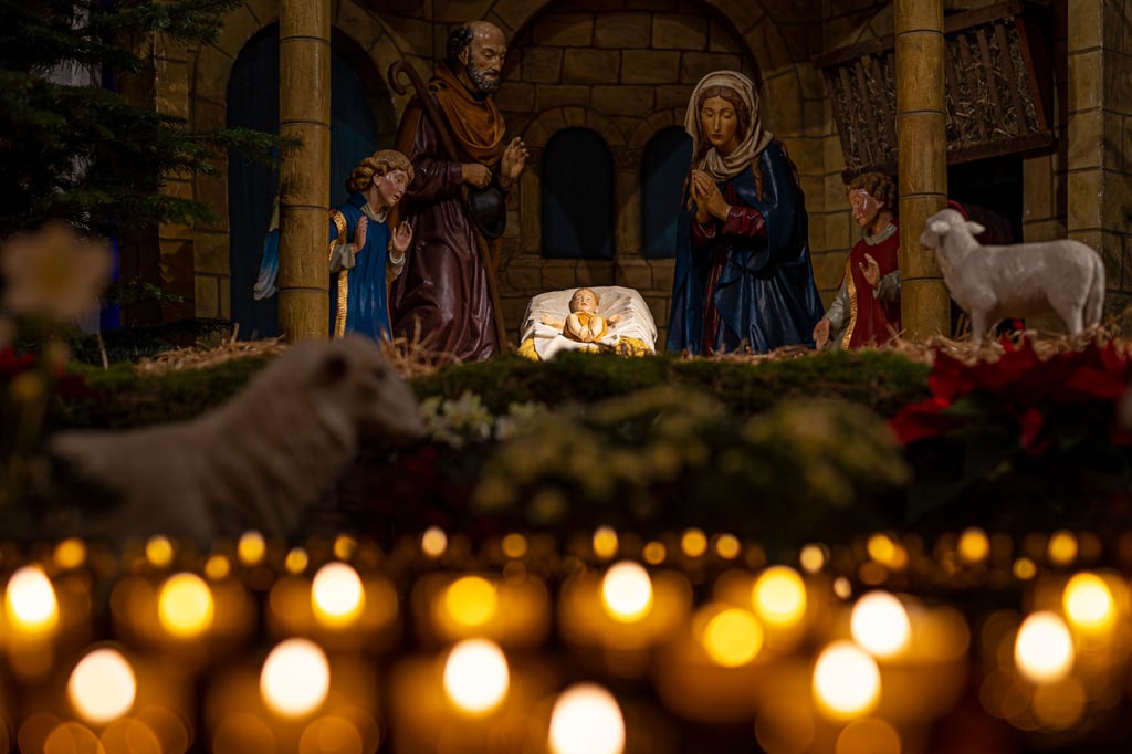 Kerzen stehen vor einer Krippe mit dem Jesuskind. Im neuen Jahr gibt es auch ein neues Motto in der Kirche. Dieses Jahr lautet es: „Alles, was ihr tut, geschehe in Liebe.“