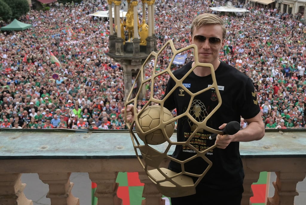 Gisli Kristjansson vom SC Magdeburg jubelt auf dem Rathausbalkon mit der Champions-League-Trophäe.