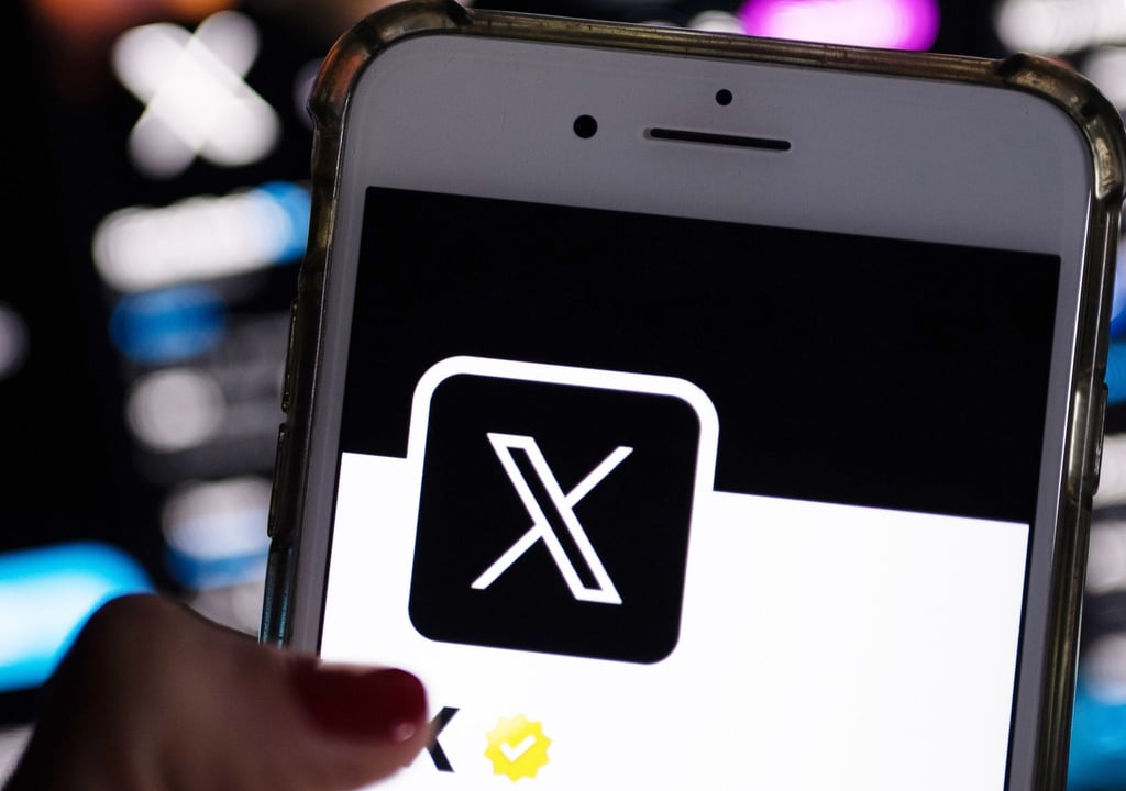 Eine Frau öffnet die App von X (ehemals Twitter) auf ihrem Handy.