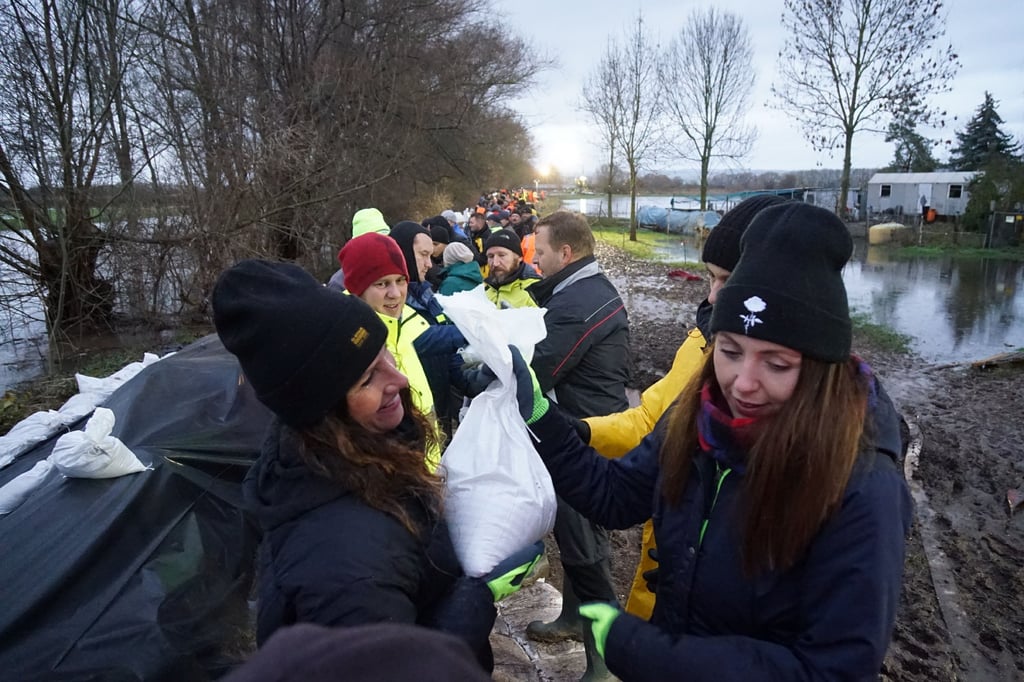 Helfer am Dienstag beim Verpacken und Stapeln von Sandsäcken an der Helme in Oberröblingen.