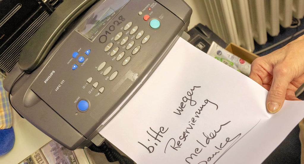 Eine Frau schiebt ein beschriebenes Blatt Papier in ein Telefaxgerät. In den Verwaltungen im Raum Köthen existieren noch einige Geräte.