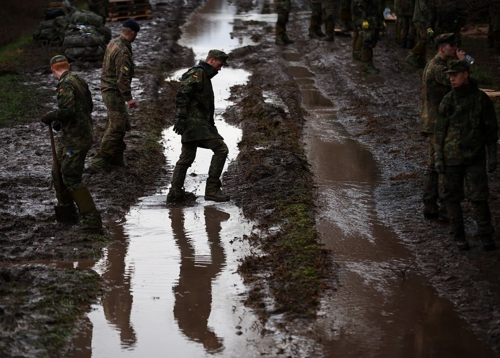 Soldatinnen und Soldaten der Bundeswehr sichern einen Deich an der Helme mit Sandsäcken.