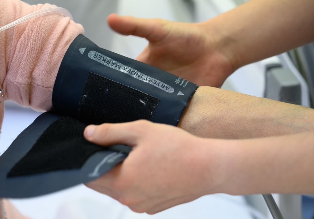Ein Pflegeabsolvent in einem Krankenhaus beim Anlegen eines Blutdruckmessgerätes.