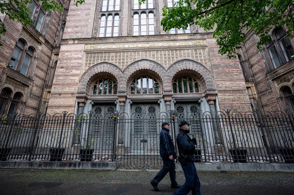 Zwei Wachleute der Polizei laufen vor dem Eingang der Neuen Synagoge Berlin vorbei.