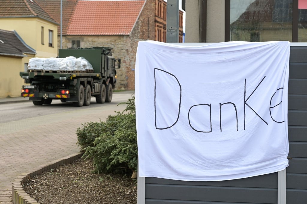 Ein Fahrzeug der Bundeswehr fährt an einem Tuch mit dem Wort "Danke" vorbei.