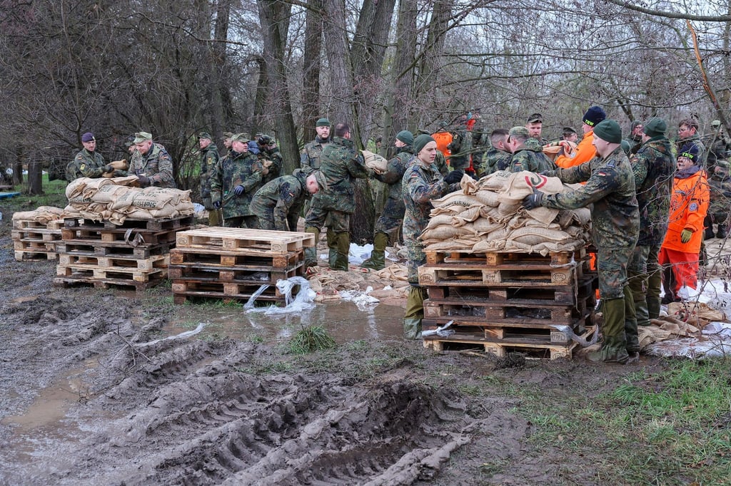 Soldatinnen und Soldaten der Bundeswehr sichern einen Deich an der Helme mit Sandsäcken.