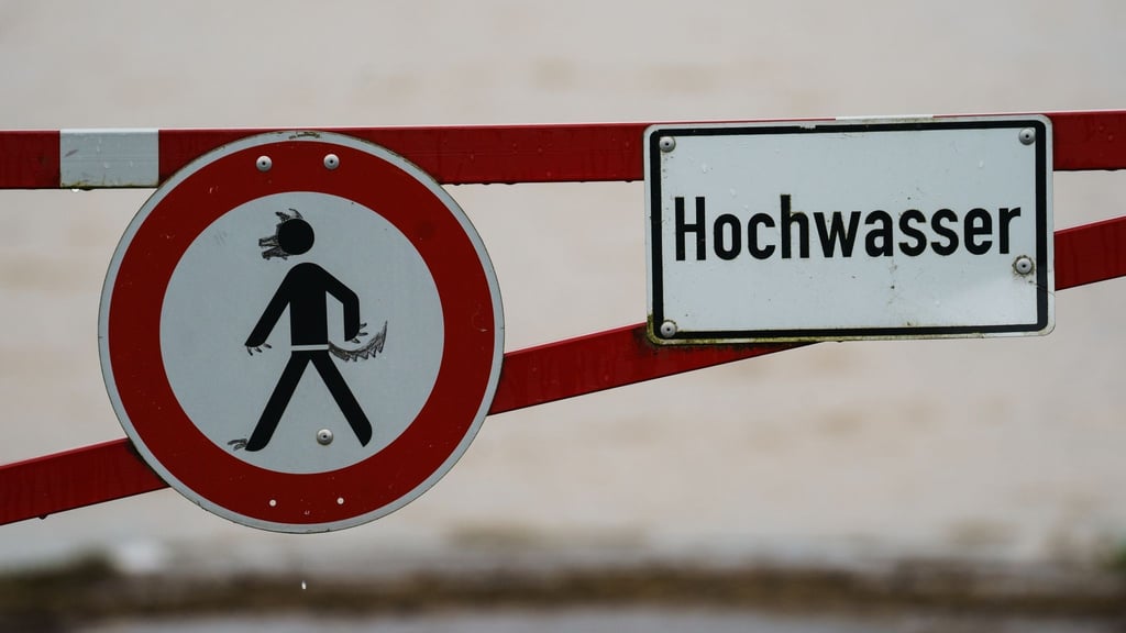 Ein Hochwasser-Schild steht an einem überfluteten Feld.