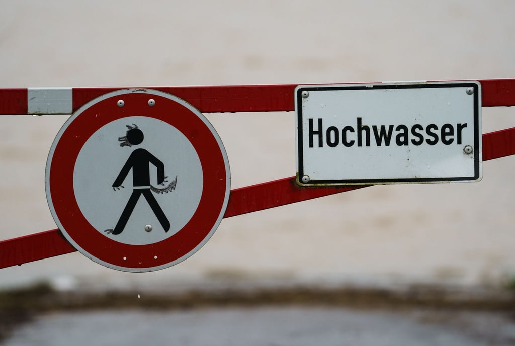 Ein Hochwasser-Schild steht an einem überfluteten Feld.