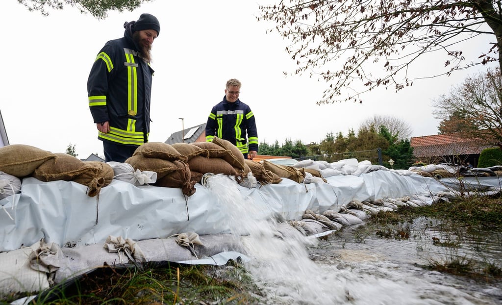 Ehrenamtliche Einsatzkräfte kontrollieren in einem Wohngebiet das Abpumpen von Wasser.